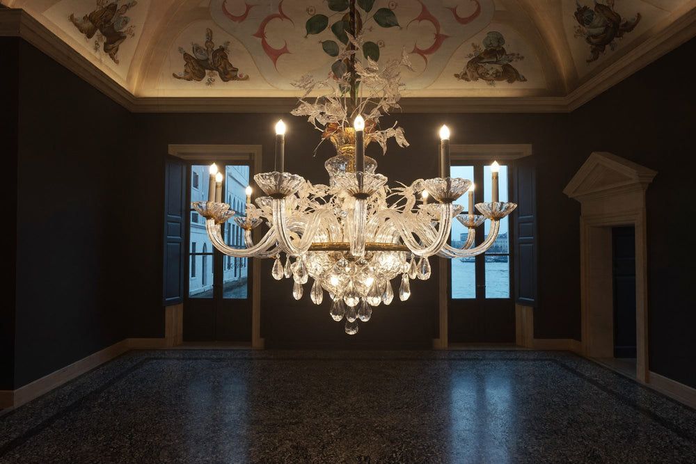 Luster od muranskog stakla upaljen u sumrak u venecijanskom palazzu, ispod stropa s freskama, s prozorima koji gledaju na kanal