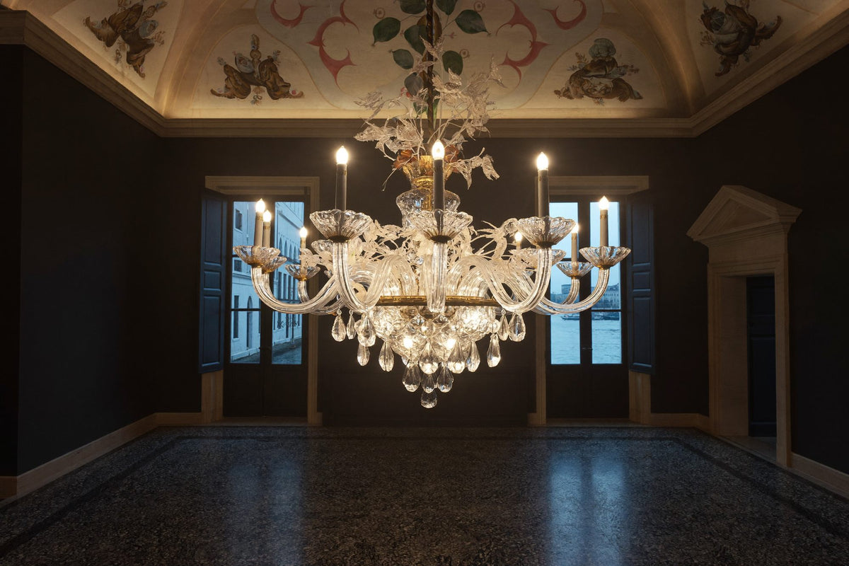 Luster od muranskog stakla upaljen u sumrak u venecijanskom palazzu, ispod stropa s freskama, s prozorima koji gledaju na kanal